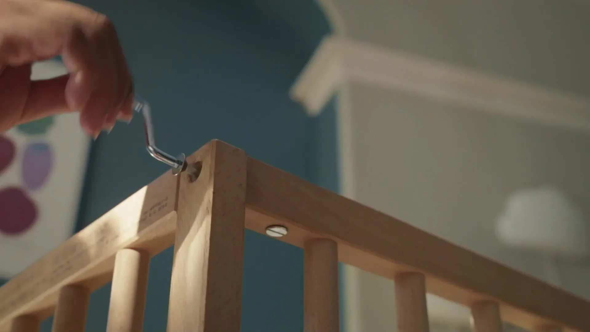 Detalle de unas manos montando la cuna de madera SNIGLAR en el anuncio de IKEA.